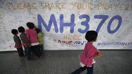 Een medewerker van Malaysia Airlines noteert een wens voor de inzittenden van vlucht MH 370 op een wand van het vliegveld in Kuala Lumpur. Foto |  AFP