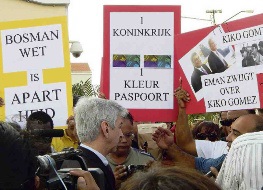 Een bewogen aankomst voor Ronald Plasterk gistermiddag. Zo’n honderd personen wachtten, hem op met borden waarop leuzen stonden geschreven als ’Eén Koninkrijk, één paspoort’ en ‘Bosman-wet is apartheid’.