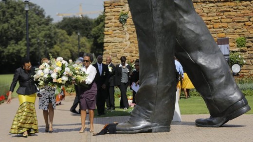 Graça Machel (links) legt bloemen neer bij het standbeeld van Mandela | EPA