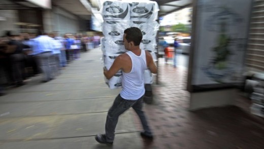 Venezolaan met een groot pak wc-papier in de hoofdstad Caracas. © AFP
