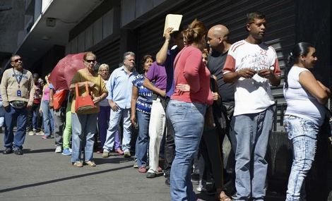 Mensen staan in de rij voor een supermarkt in Caracas, nadat president Maduro de economische noodtoestand uitriep. | Foto: AFP