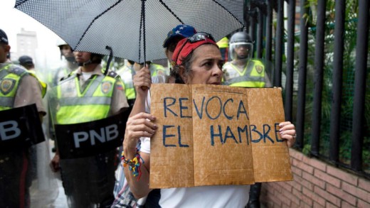  Een Venezolaanse vrouw houdt een bord omhoog met 'Stop de honger'. Door de aanslepende economische en politieke crisis lijdt de Venezolaanse bevolking al maanden honger. © AP 