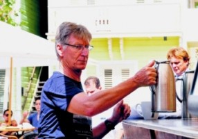 Een toerist van het Kura Hulanda resort bedient zichzelf van koffie.